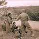 A US soldier offers food to Japanese women gathered on a roadside, Okinawa, 1945